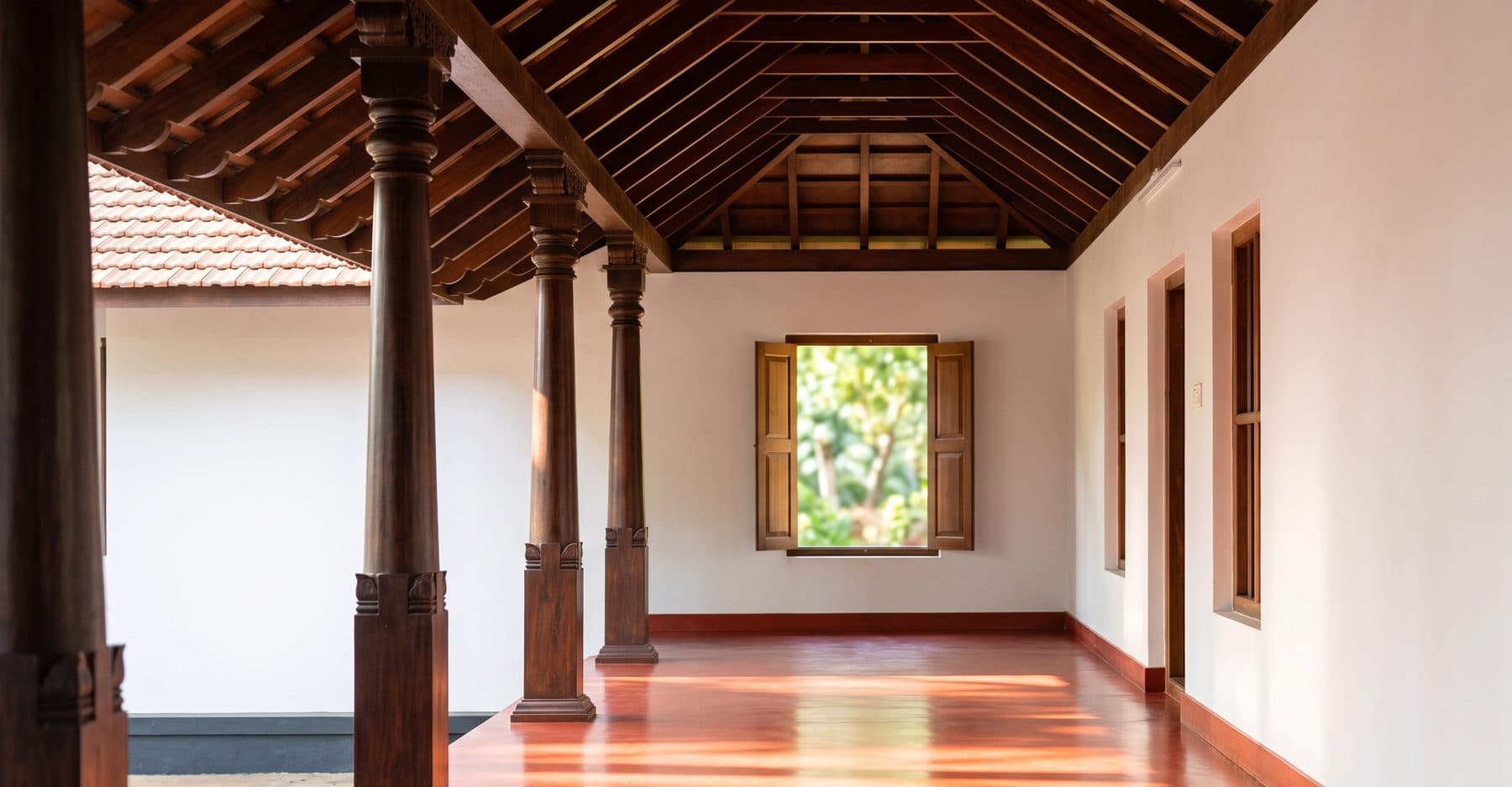 An empty Kerala verandah with wooden pillars in morning light